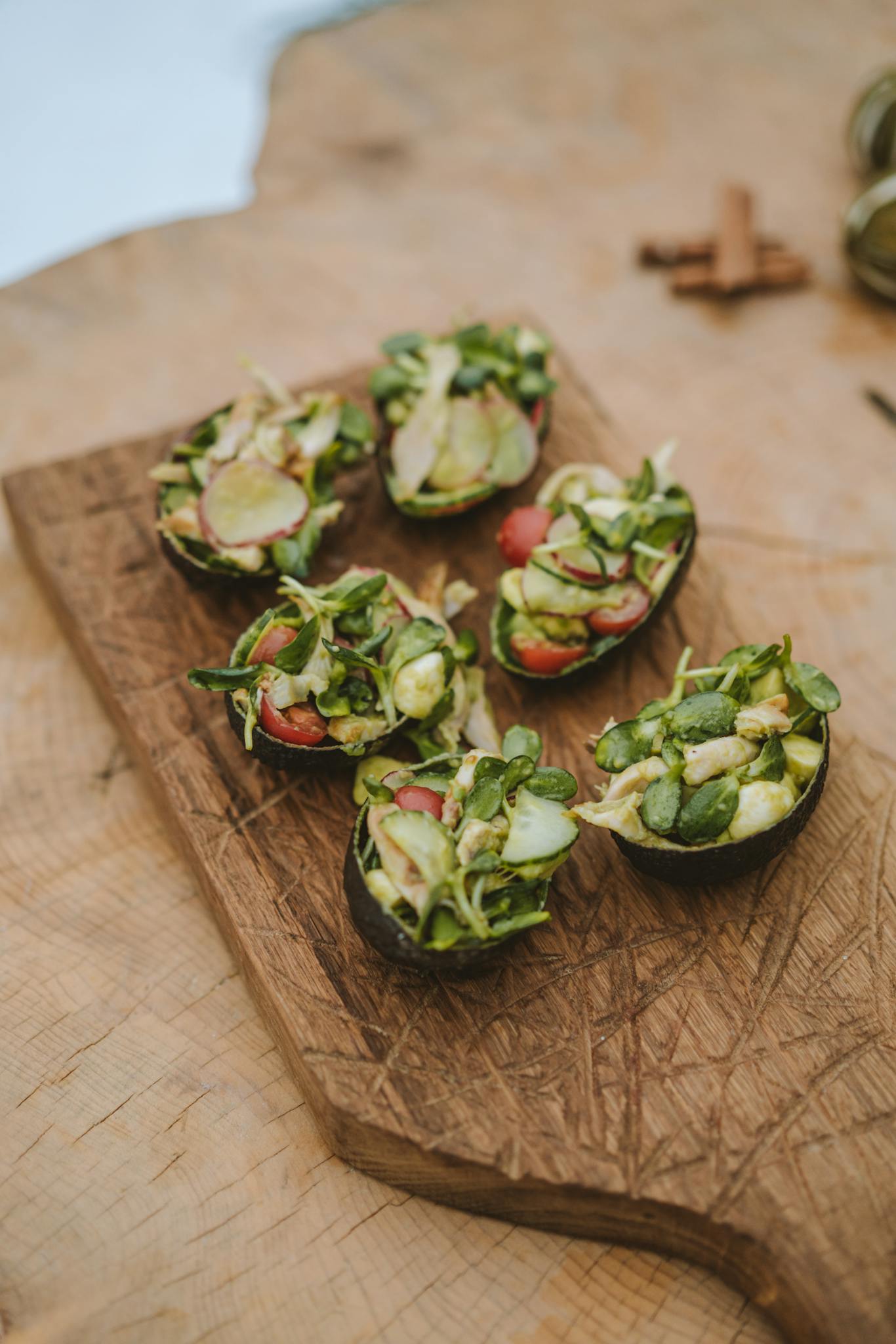 Savory avocado halves filled with fresh vegetables on a rustic wooden board for a healthy appetizer.
