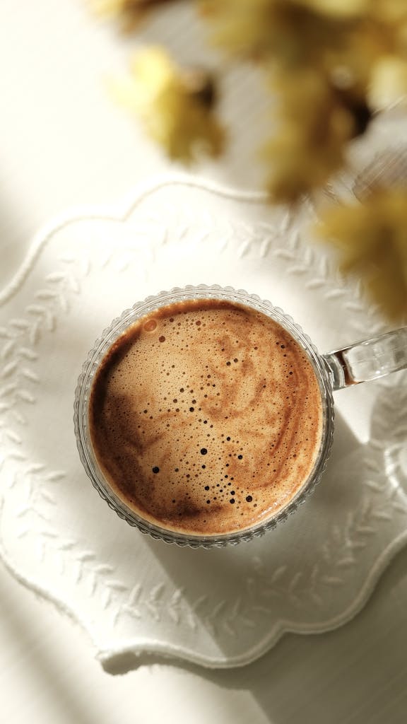 Top view of a delicious coffee in a glass cup with floral decor. Perfect for cozy morning inspiration.